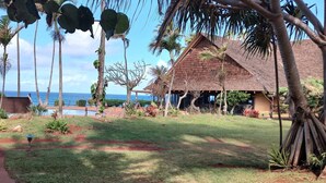 Un hotel tropical amb piscina, palmeres i vistes a l'oceà.