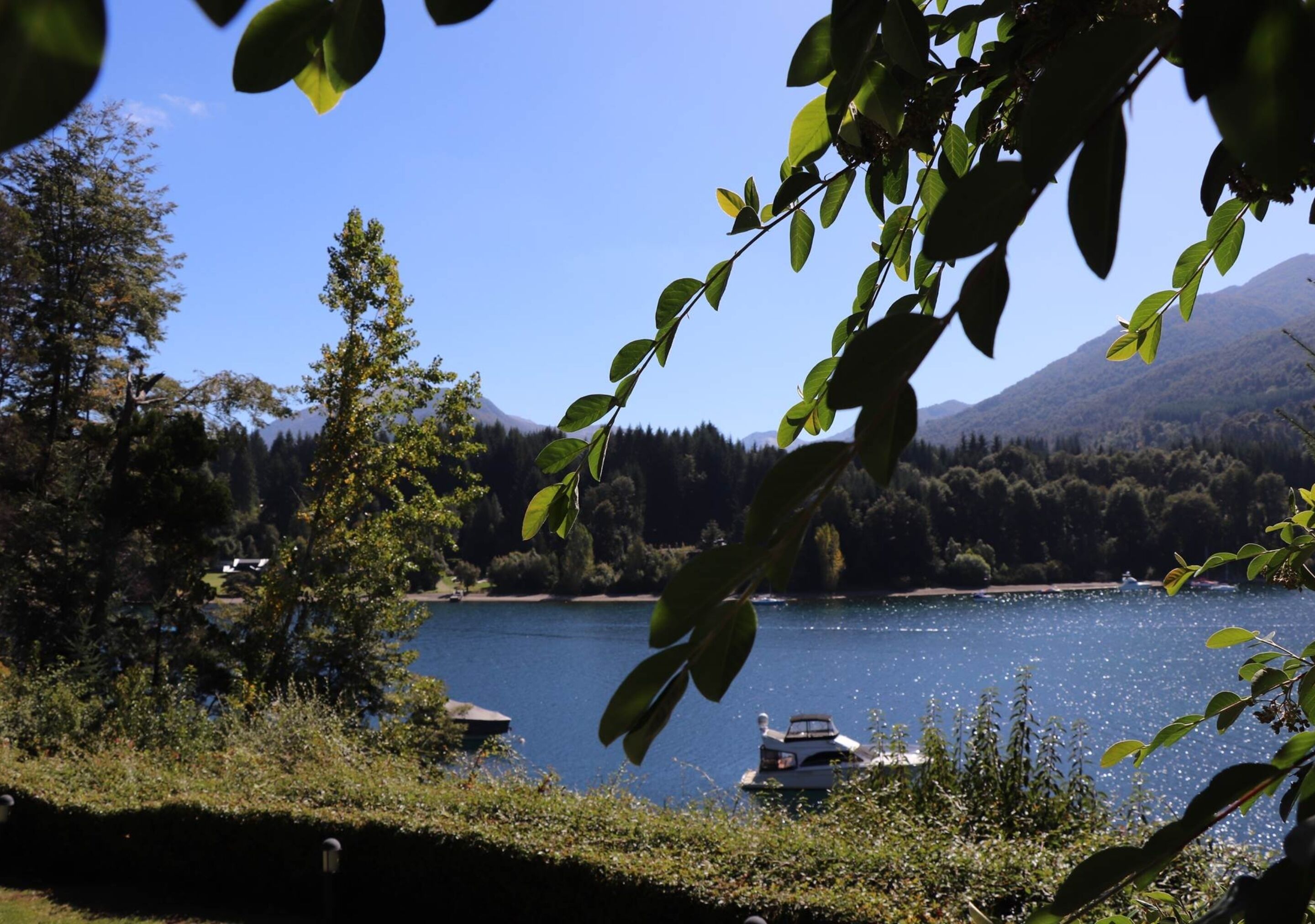 A lake with a boat, surrounded by trees and mountains.