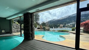 An indoor swimming pool with a view of a mountain landscape and a lake. - El Muelle by DOT Boutique (Villa La Angostura)