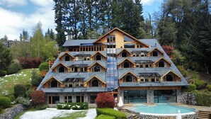 A multi-story log cabin with a swimming pool and deck chairs. - El Muelle by DOT Boutique (Villa La Angostura)