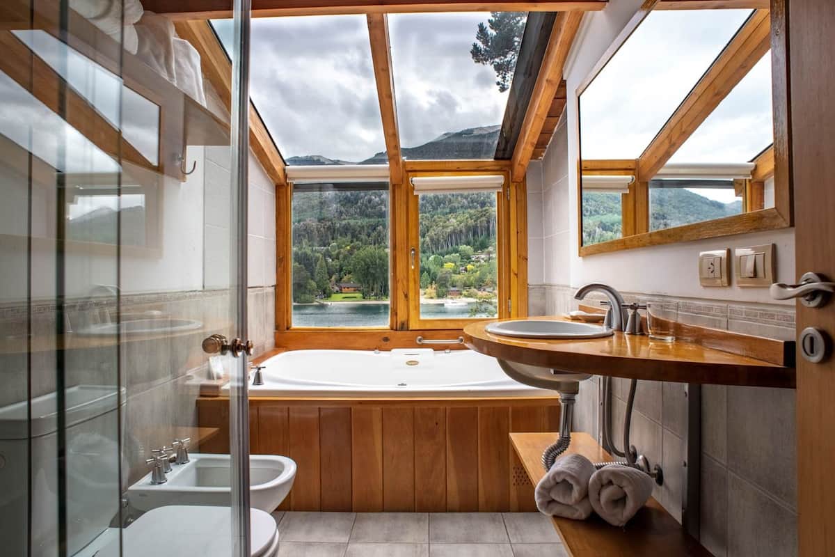 A modern bathroom with a large skylight, a freestanding bathtub, a sink, and a glass-enclosed shower.