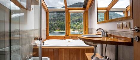 A modern bathroom with a large skylight, a freestanding bathtub, a sink, and a glass-enclosed shower.