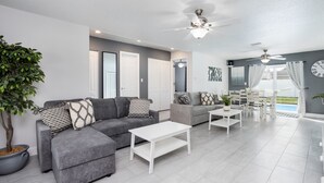 A modern living room with grey sofas, white coffee tables, and a ceiling fan. - House in Melbourne With Pool (Melbourne)