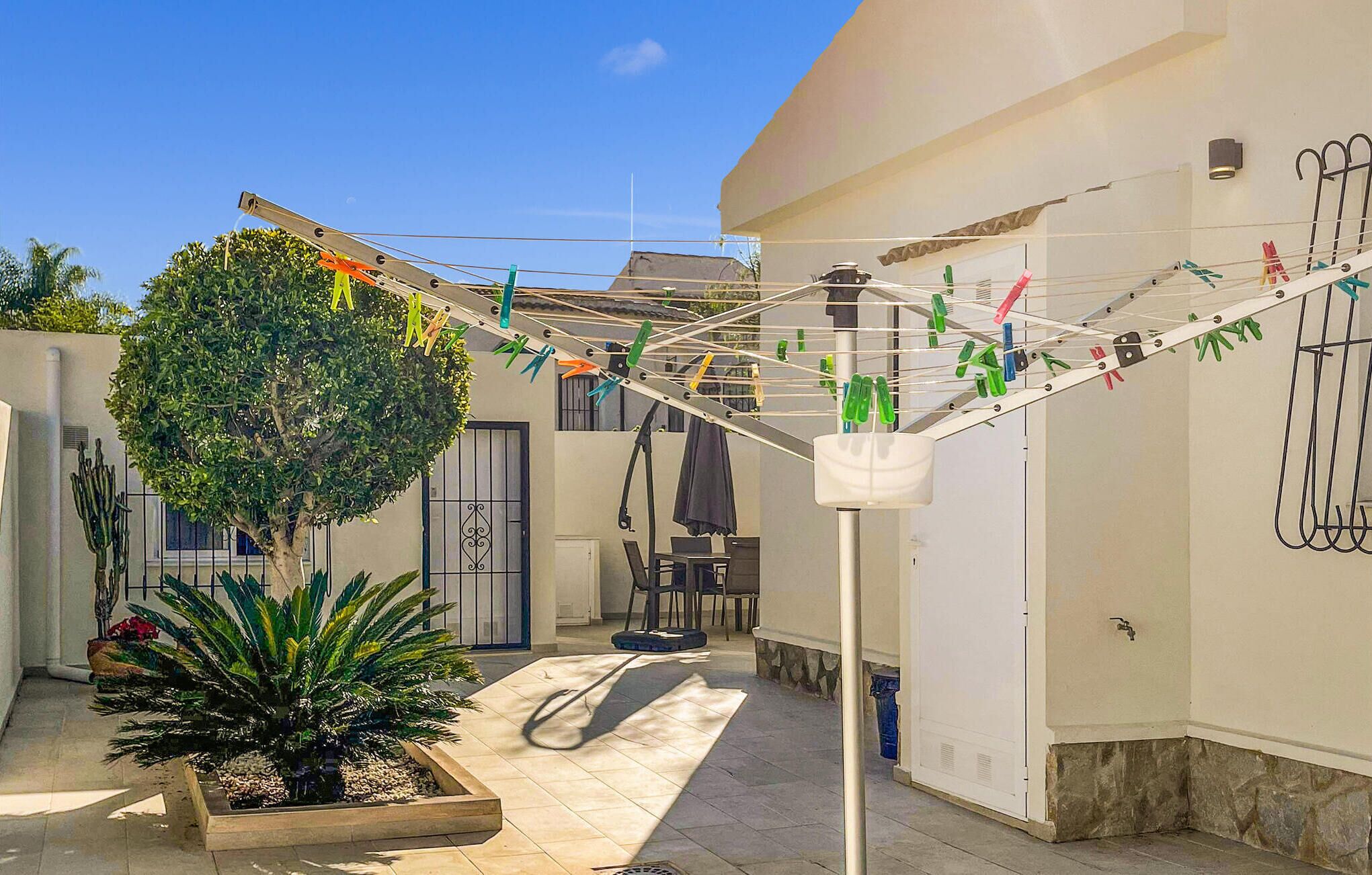 A courtyard with a drying rack, a potted plant, and a wall-mounted drying rack.