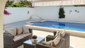 A poolside area with wicker furniture and a small pool.