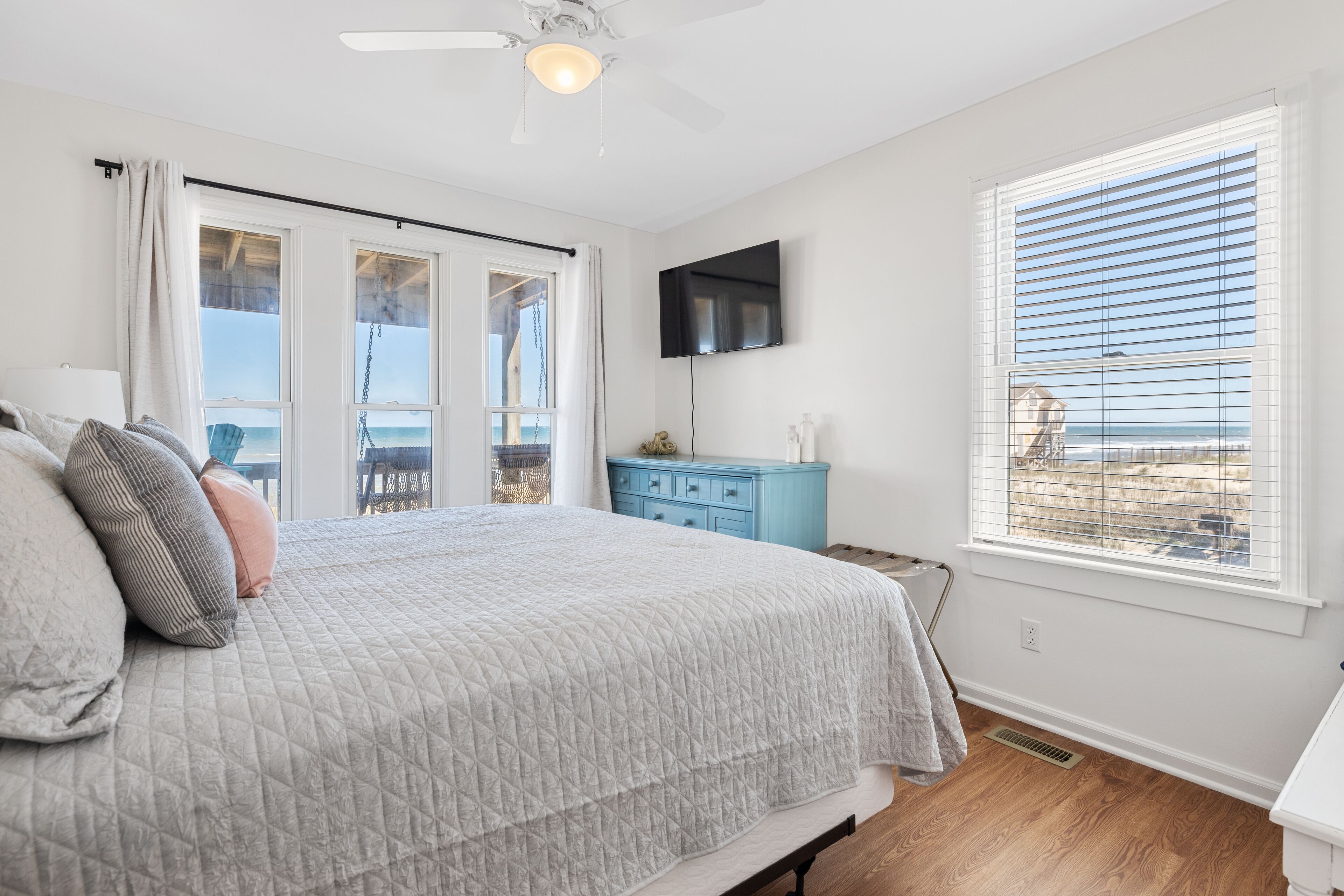 A bedroom with a bed, a TV, a dresser, and a window with a view.