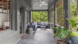 A covered porch with a ceiling fan, a sofa with cushions, a coffee table, and potted plants. - Historic Hidden Gem - Downtown Southern Pines (Southern Pines)