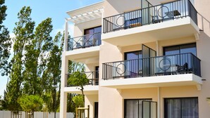 Ein mehrgeschossiges Wohnhaus mit Balkonen, einer gepflasterten Auffahrt und einem angelegten Garten.