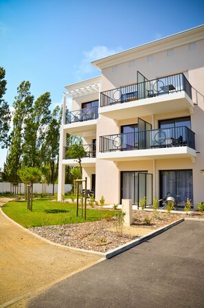 Un edificio residenziale a più piani con balconi, vialetto e giardino curato.