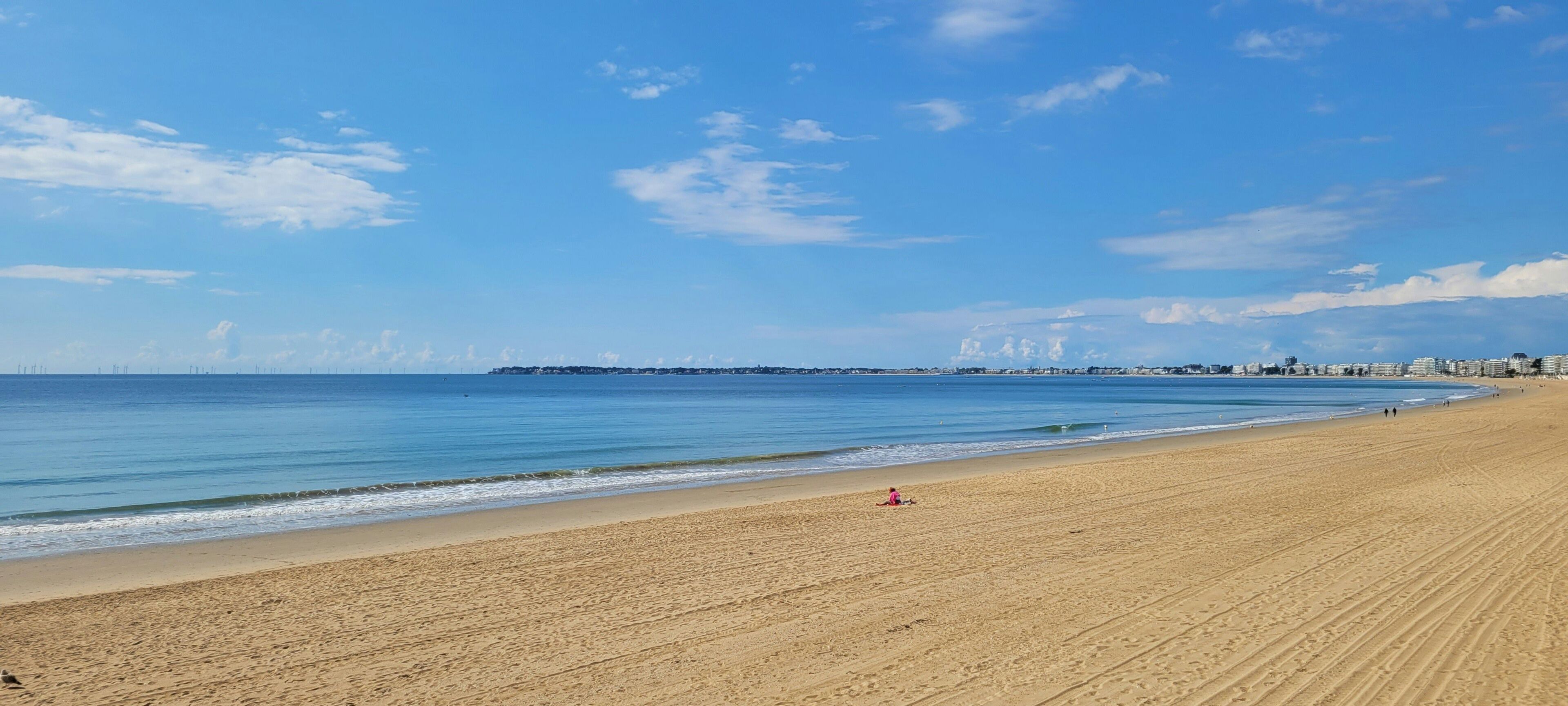 A wide sandy beach with a clear blue sky and calm sea.