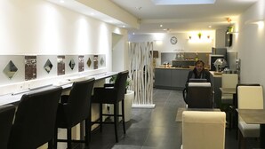 Ein modernes Restaurant mit Barbereich, Sitzgelegenheiten und einer Küche im Hintergrund.