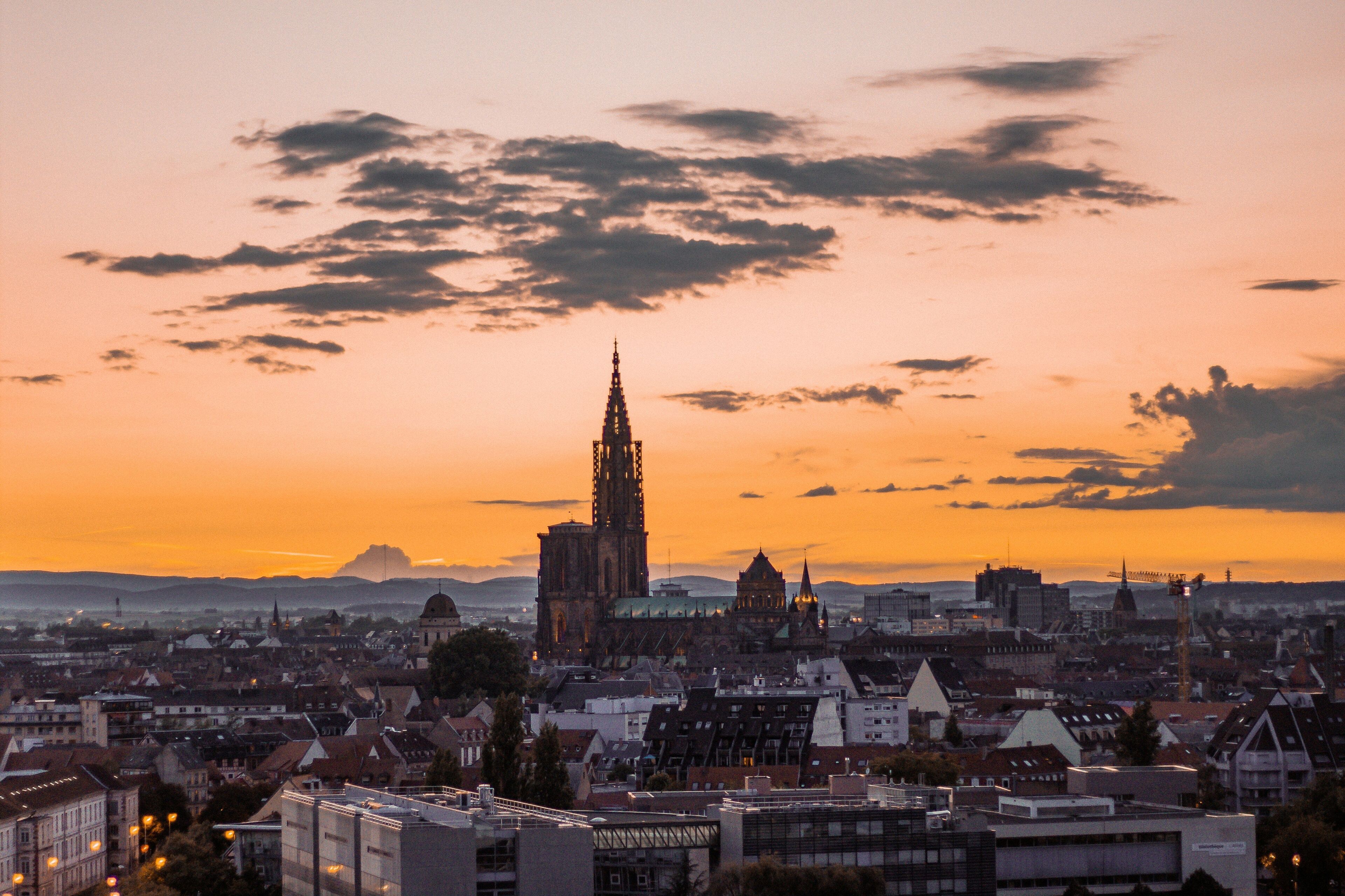 Une vue urbaine avec une cathédrale imposante, prise au coucher du soleil.