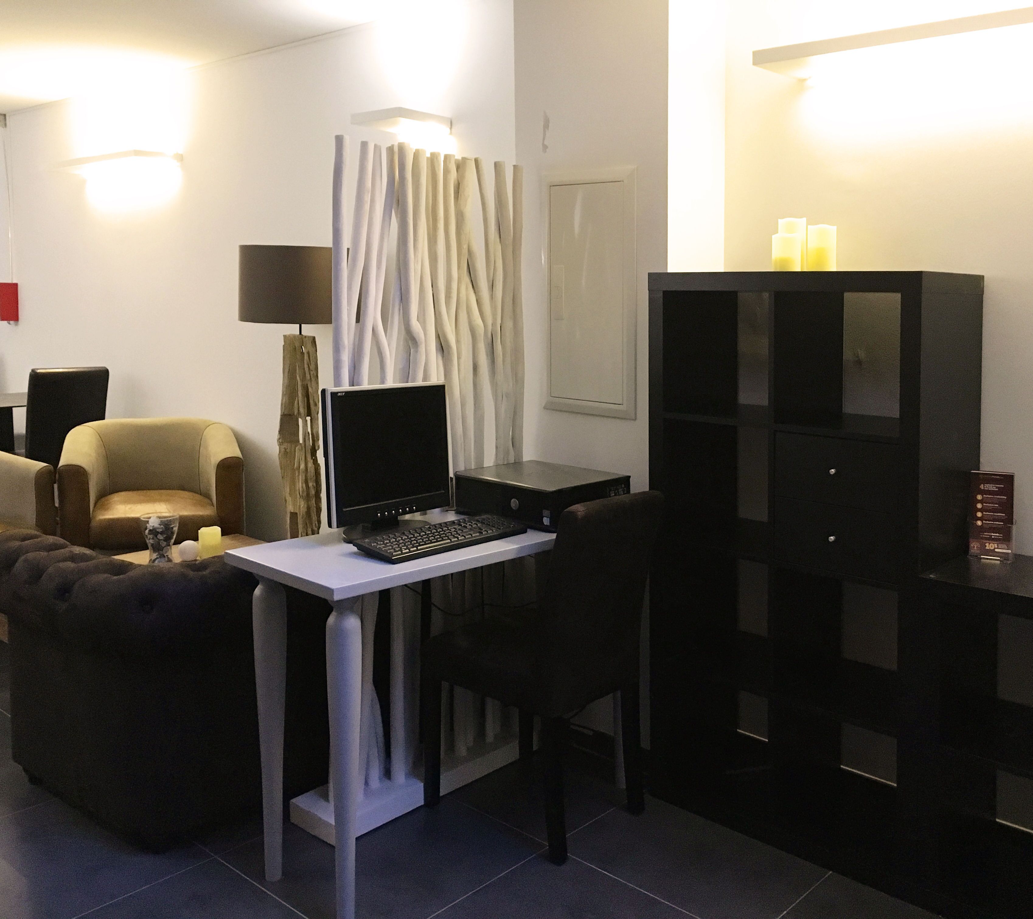 Un espace de vie compact comprenant un bureau, un ordinateur et un coin salon.
