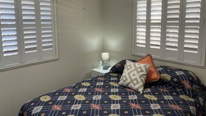 Un dormitorio con cama, mesita de noche, lámpara y ventilador de techo.