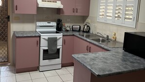 Una cocina con gabinetes rosados, una estufa blanca y una encimera gris.
