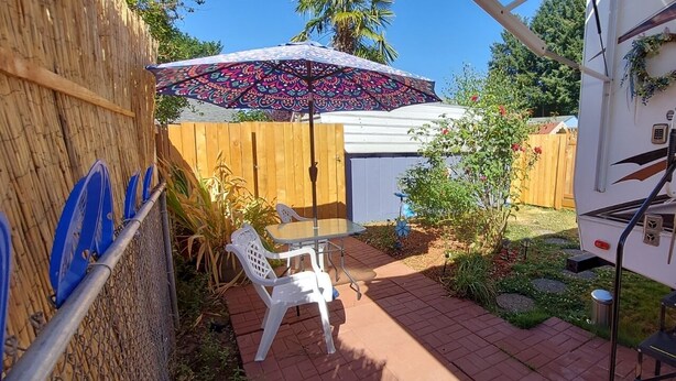 Un patio trasero con un porche, una mesa y una silla.