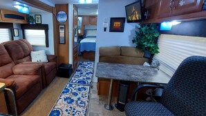 Interior compacto de una autocaravana con sofá, mesa de comedor y zona de cocina.