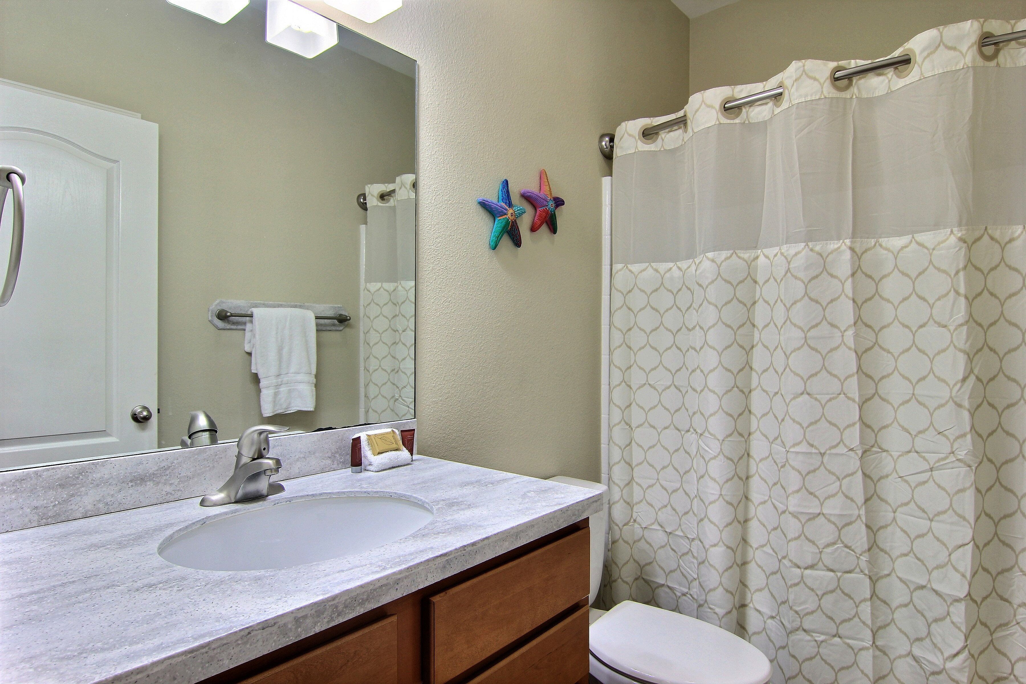 A bathroom with a white sink, a mirror, a towel rack, and a shower curtain.