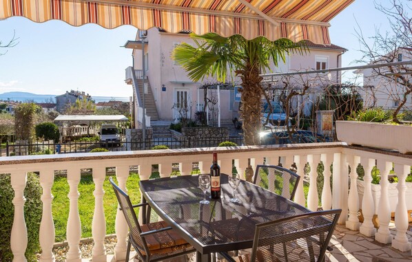 Ein Balkon mit Tisch, Stühlen, einer Weinflasche und einem Palmenbaum.