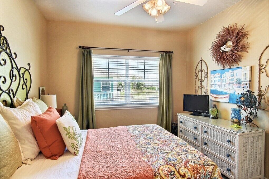 A bedroom with a bed, curtains, a television, and decorative items.
