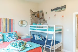 A child's bedroom with bunk beds, a dresser, a mirror, and wall decorations including fish and a turtle. - Soulshine by Silver Sands Vacation Rentals (Port Aransas)