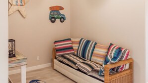 Una habitació acollidora amb un sofà estampat, una decoració de estrella de mar i una il·lustració de cotxe a la paret.