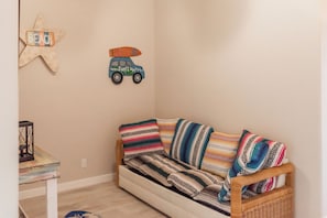 A cozy room with a striped sofa, a starfish decoration, and a car illustration on the wall. - Soulshine by Silver Sands Vacation Rentals (Port Aransas)