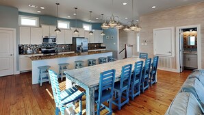 A spacious kitchen with a central island, bar stools, and pendant lighting. - Turtle Paradise by Silver Sands Vacation Rentals (Port Aransas)