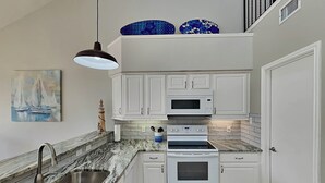 A kitchen with white cabinets, a double oven, a microwave, and a sink. - Sol Searcher by Silver Sands Vacation Rentals (Port Aransas)