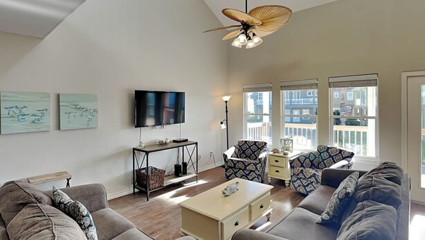 A modern living room with a sofa set, a coffee table, a TV, and a ceiling fan. - Sol Searcher by Silver Sands Vacation Rentals (Port Aransas)