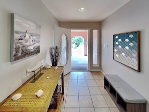 A hallway with a wooden table, a bench, and artwork on the walls. - Sol Searcher by Silver Sands Vacation Rentals (Port Aransas)