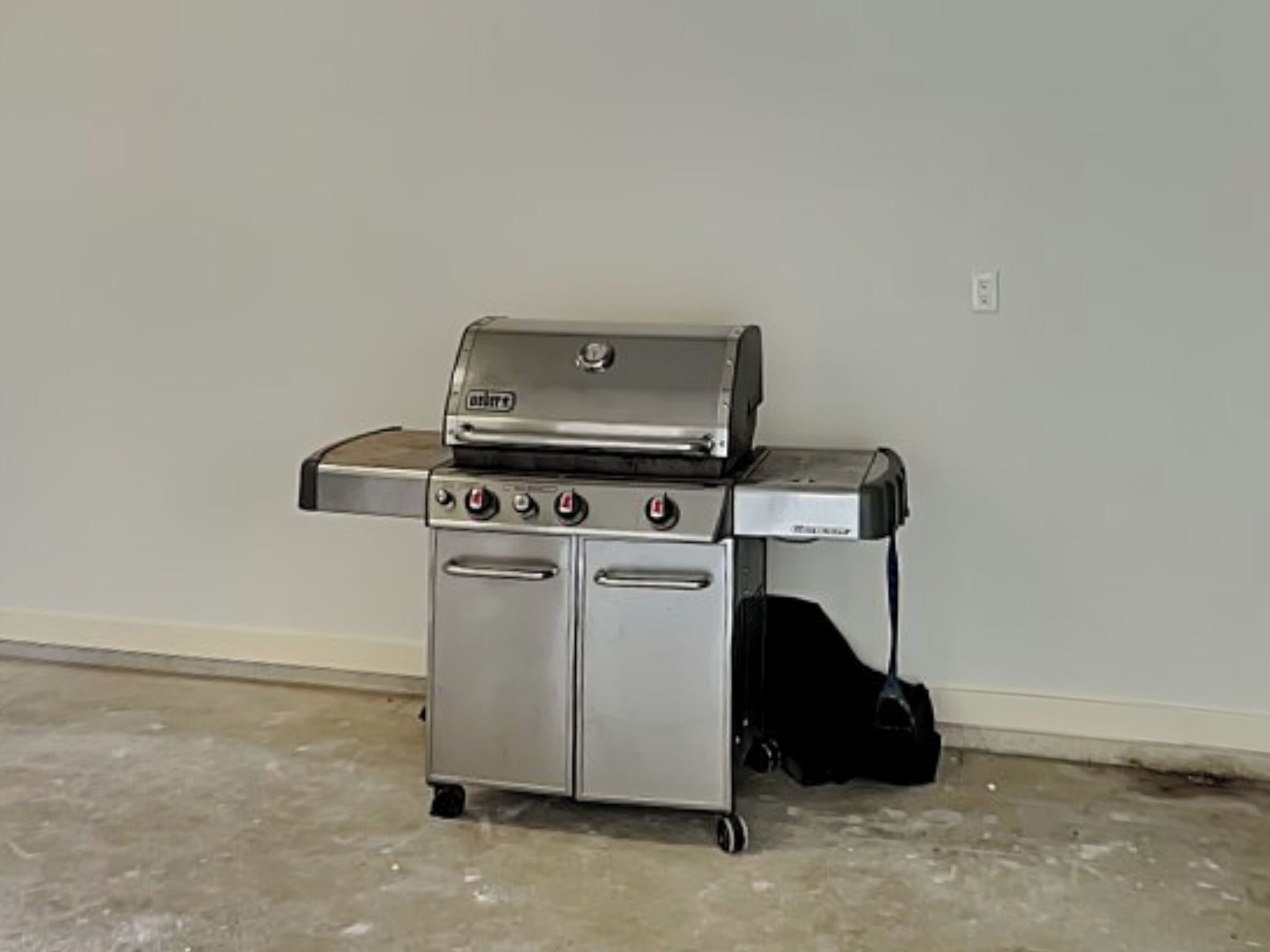A portable stainless steel grill with a built-in oven, a side burner, and a storage compartment.