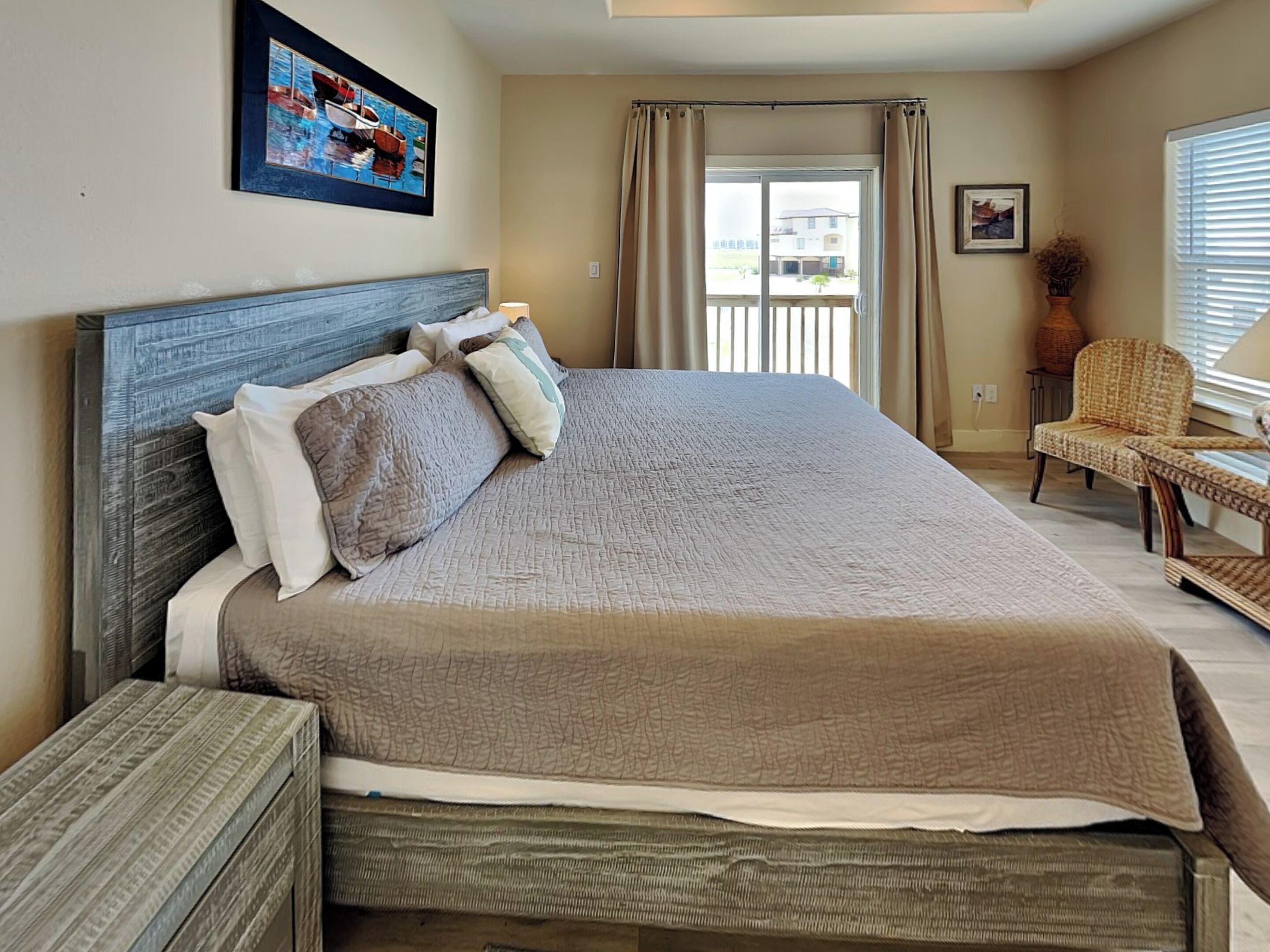 A bedroom with a large bed, a chair, a window with curtains, and a painting on the wall.