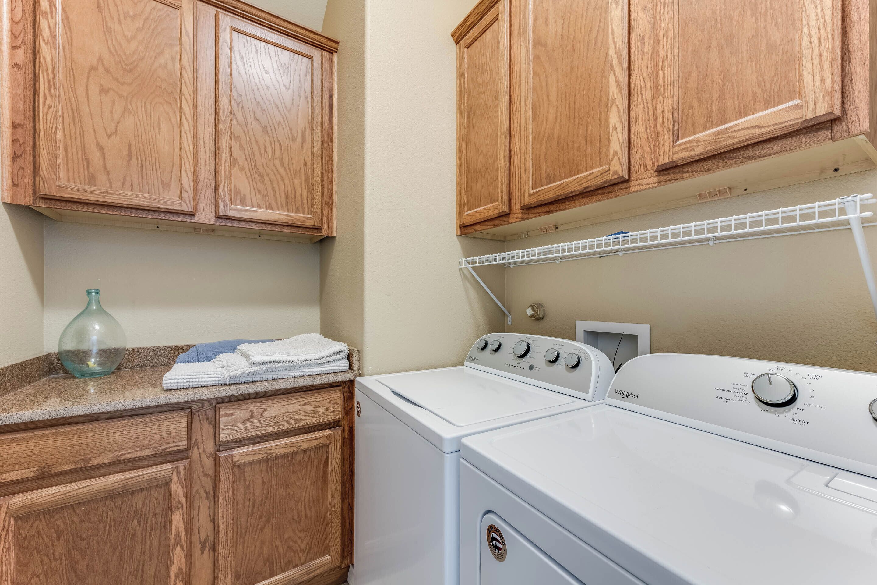 A laundry area with wooden cabinets, a washing machine, and a drying rack.