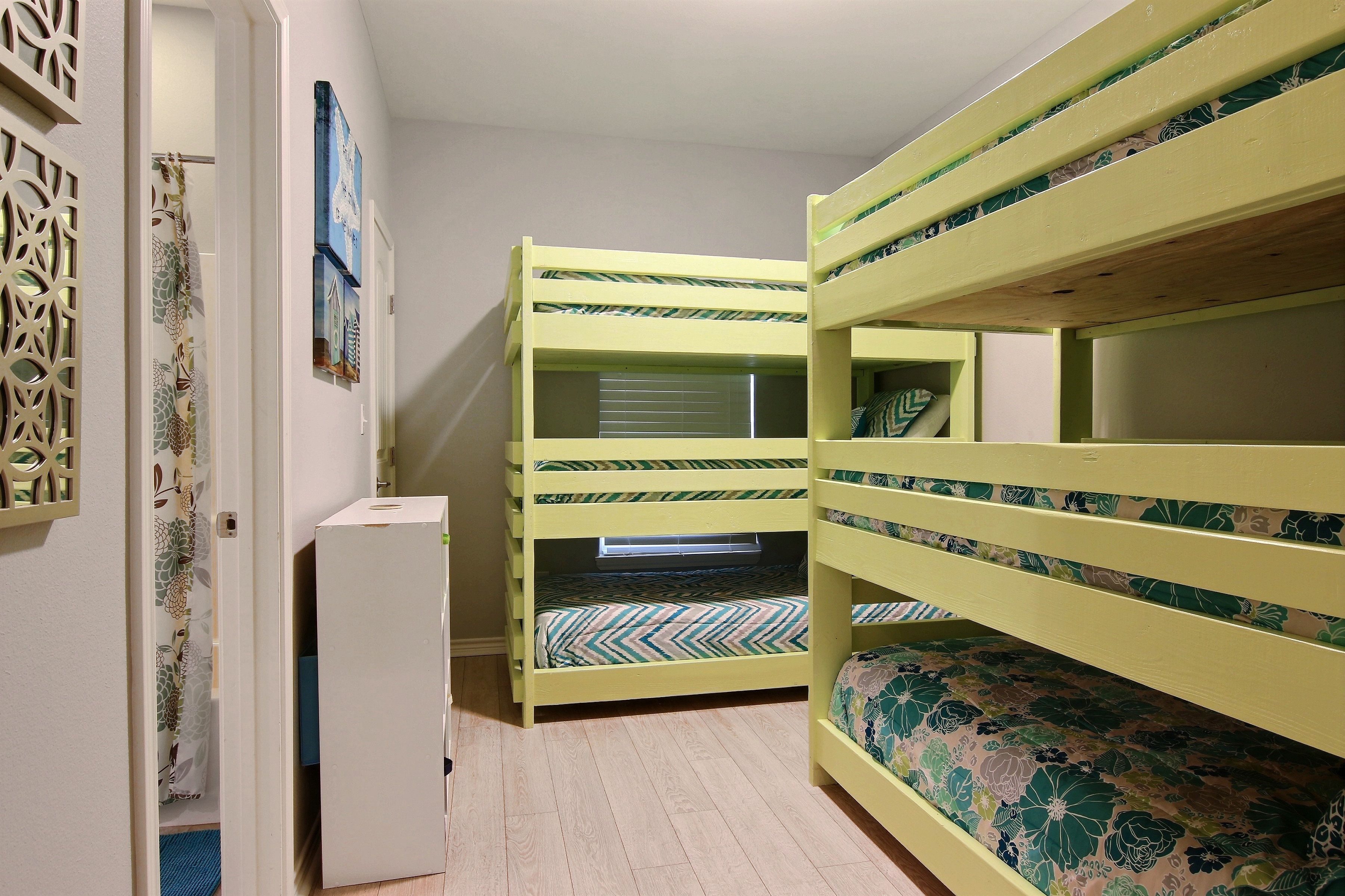 Een kamer met stapelbedden en een klein wit kastje.