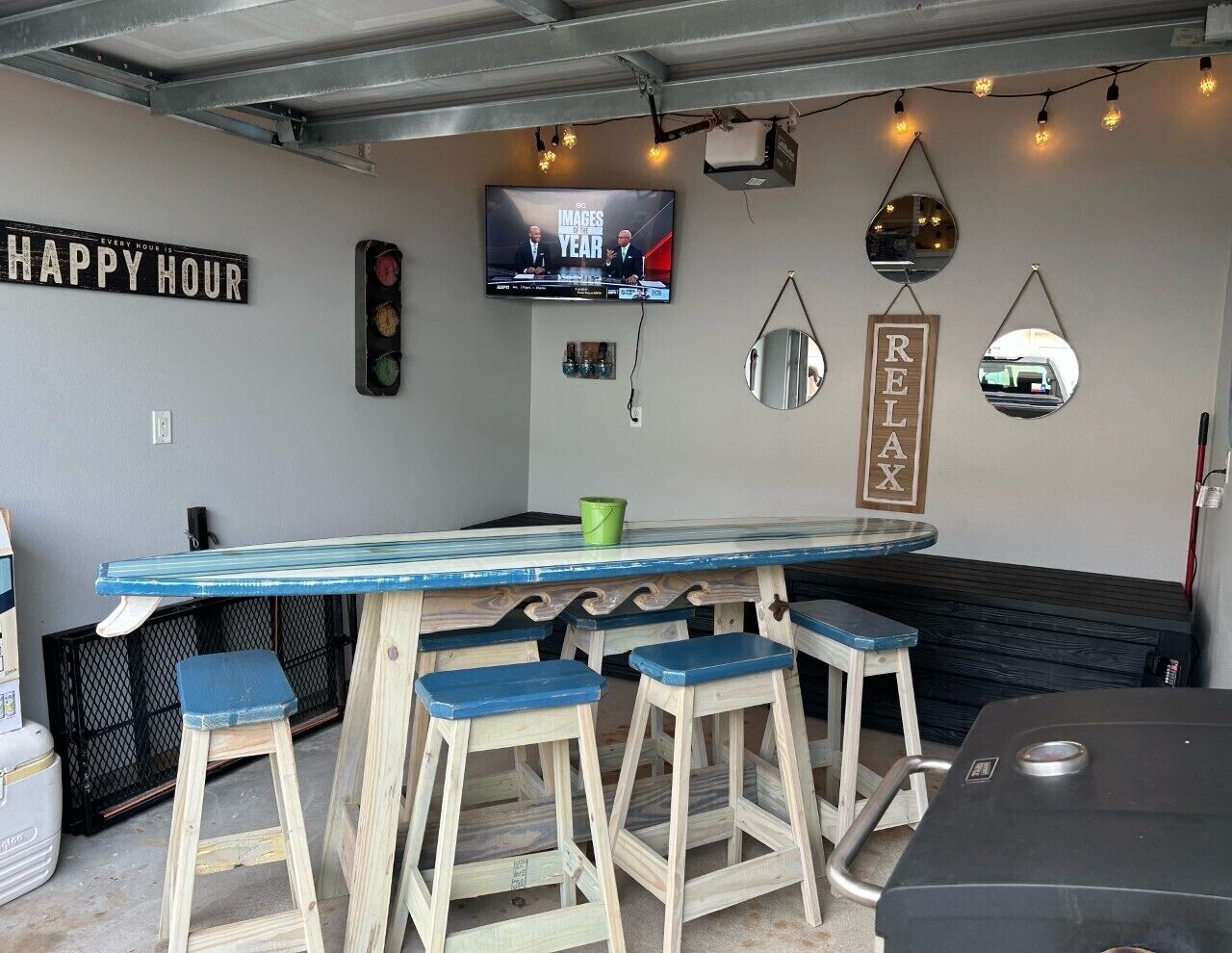 A bar area with a wooden bar top, blue bar stools, a television, and a 'RELAX' sign on the wall.