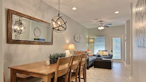 A dining area with a wooden table and chairs, a chandelier, and a ceiling fan. - Surfin' Seahorse by Silver Sands Vacation Rentals (Port Aransas)