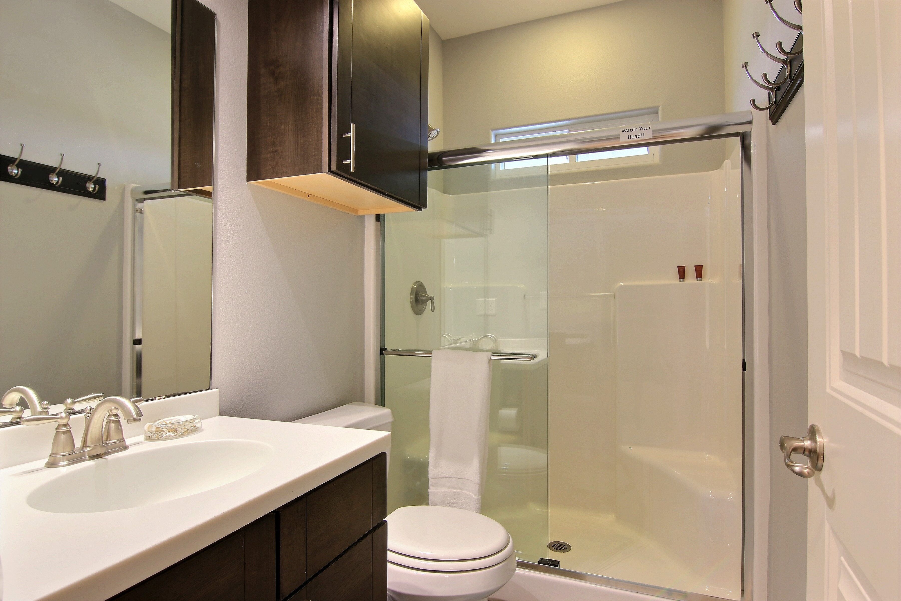 Une salle de bain avec un lavabo blanc, des toilettes et une douche à parois de verre.