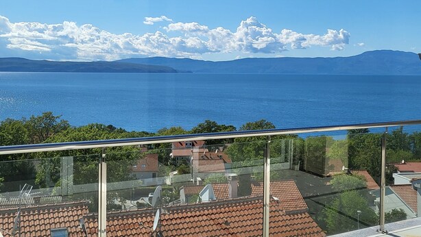 Un balcone con vista libera sul mare e montagne lontane.