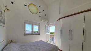Una camera da letto con un letto, un armadio, una finestra e un elemento decorativo al muro.
