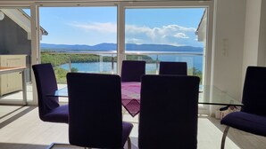 Un balcone con tavolo e sedie, vista su un lago e montagne.