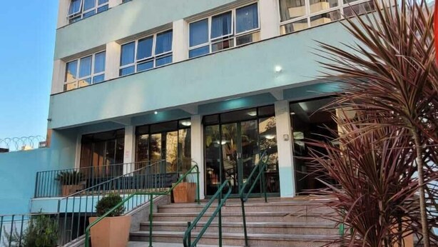 A multi-story building with a flat facade, large windows, and a central entrance with a staircase. - Vicz Palace Hotel (Curitiba)