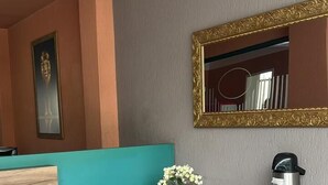 A modern kitchen with a teal accent wall, a wooden cabinet, a black countertop, a stainless steel coffee maker, and a mirror with a gold frame. - Vicz Palace Hotel (Curitiba)