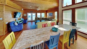 A wooden interior with a dining table, chairs, a sofa, and a television. - The Fire Escape by Silver Sands Vacation Rentals (Port Aransas)