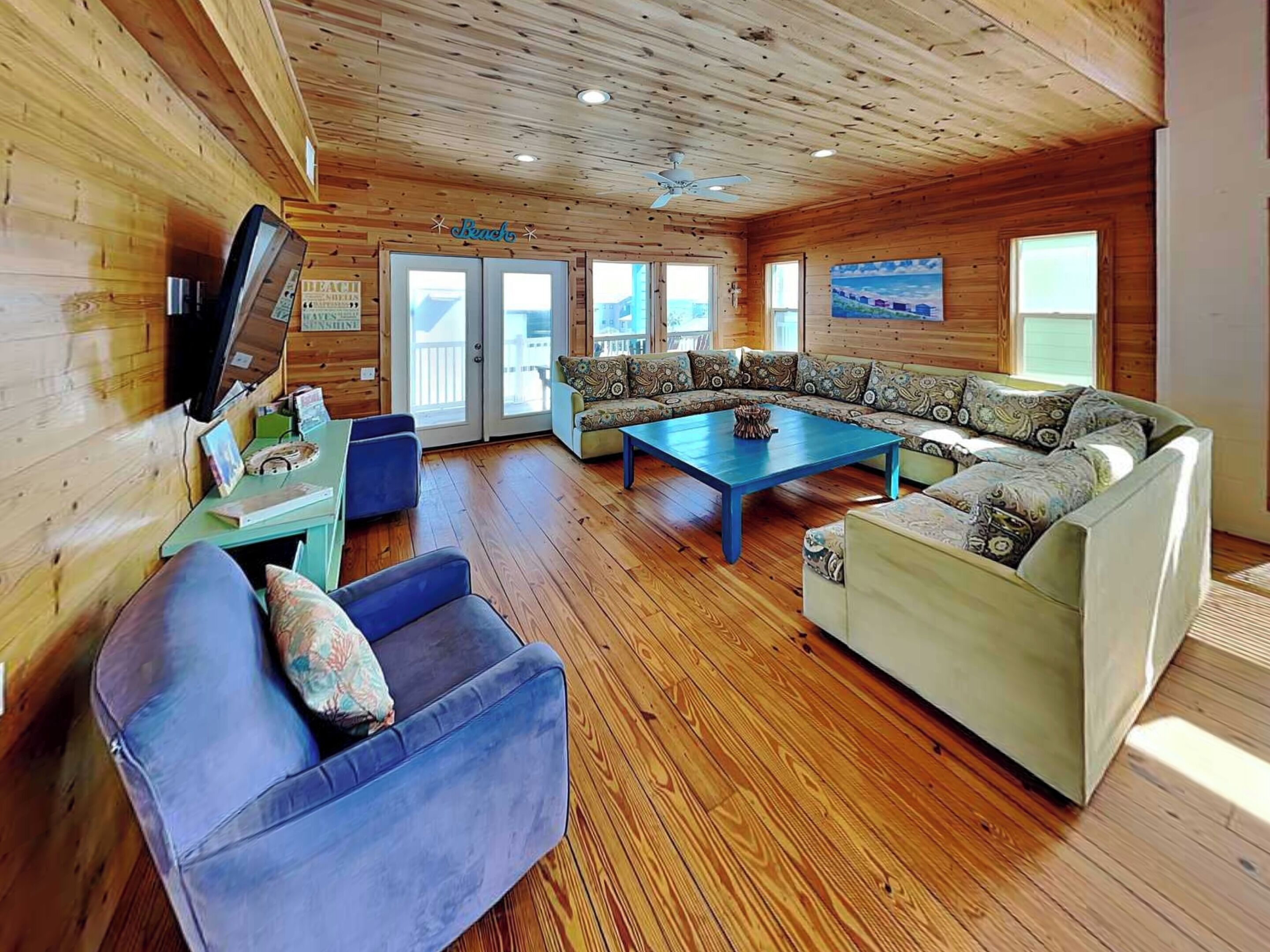 A wooden interior with a sofa, a coffee table, and a television.