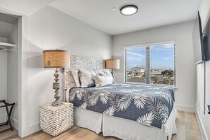 Une chambre à coucher avec un lit, des lampes de chevet, une fenêtre avec des stores et une vue sur des immeubles.