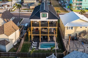A two-story house with a balcony, a swimming pool, and a fenced yard. - The Gentry by Silver Sands Vacation Rentals (Port Aransas)