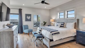 Ein Schlafzimmer mit Bett, Schreibtisch, Stuhl, Bank und Deckenventilator.