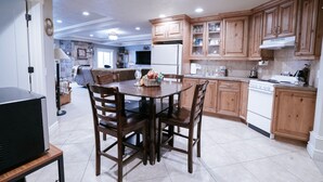 A modern kitchen with wooden cabinets, a dining table with chairs, a refrigerator, and a stove. - Family FUN at the Homestead with Pool & Ping Pong, Karaoke & more! Great Value! (Brigham City)