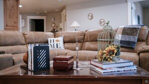A living room with a leather sofa, a coffee table with books and a decorative birdcage. - Family FUN at the Homestead with Pool & Ping Pong, Karaoke & more! Great Value! (Brigham City)